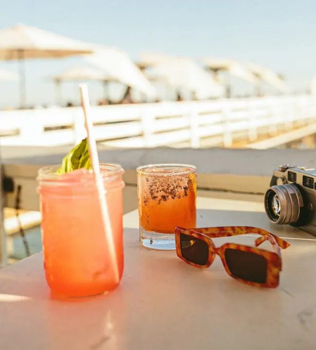 Margarita, sunglasses, and vintage camera on a table at Malibu Pier