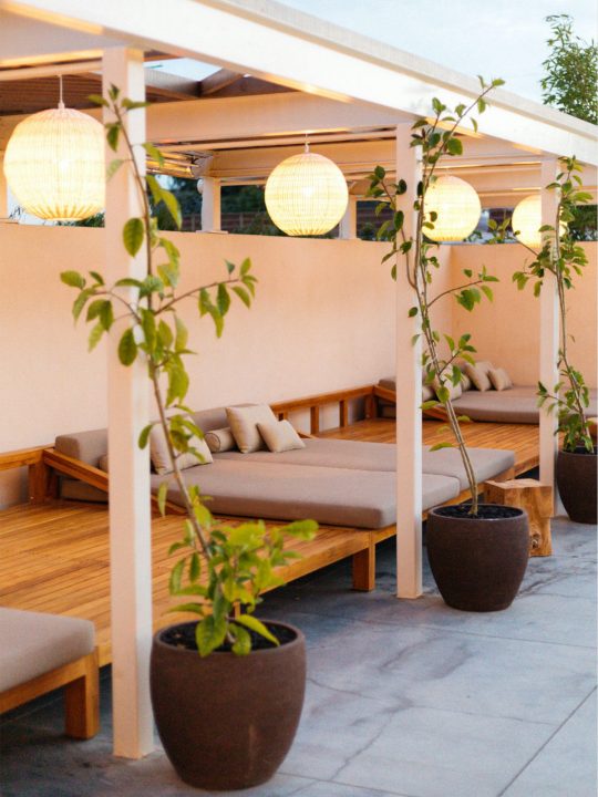 Poolside cabans with potted platnts, lounge cushions and globe lamps above