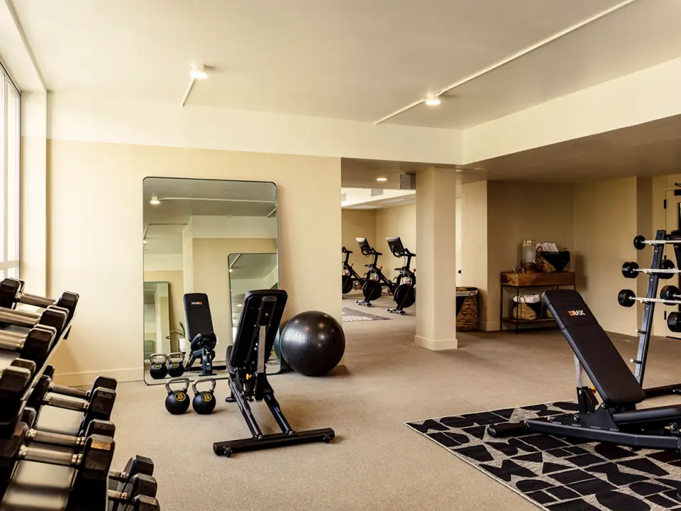 Fitness rooms with excercise equipment, weights, mirror and spinning bikes in adjacent room