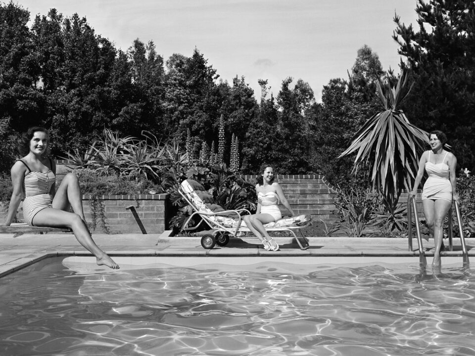 Old black and white image of three ladies posing by the pool