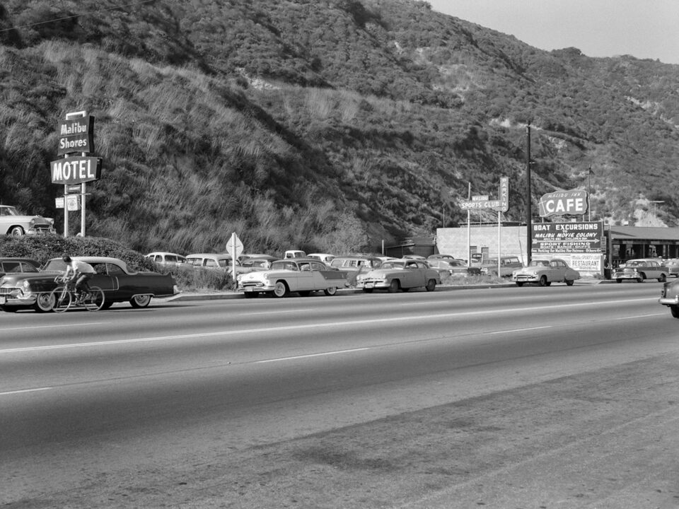old black and white image of cars driving down pacific coast highway